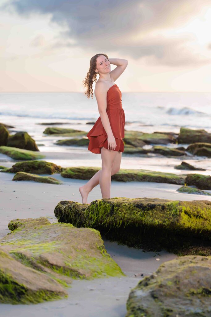 Senior Portraits standing on moss rocks at Kure Beach